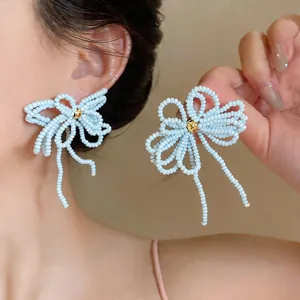 Gros plan de boucles d'oreilles nœud en perles de verre bleu clair fait main.