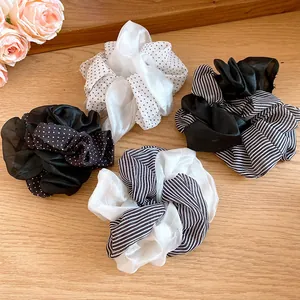 Close-up of polka dot and striped fabric scrunchies in black and white tones.
