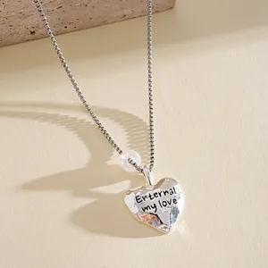 Gros plan détaillé du pendentif cœur en argent avec gravure de texte Enternal my love.