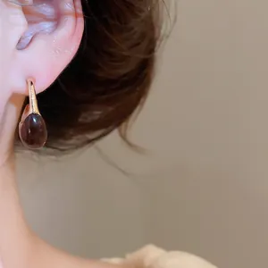 Close-up detail view of a vintage Maillard style resin C-shaped earring worn on ear.