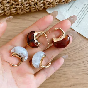 Close-up of vintage Maillard resin C-shaped earrings with marble and tortoiseshell patterns