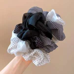 Close-up detail of oversized chiffon scrunchies with elegant polka dot and stripe patterns