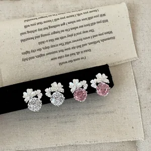 Primo piano di orecchini a fiore scintillanti rosa e bianchi su velluto nero