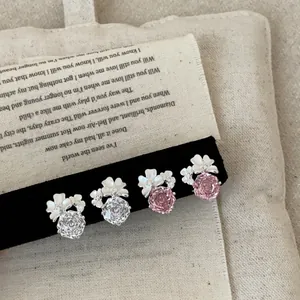 Dettaglio di eleganti orecchini a fiore con cristalli rosa e bianchi su velluto nero