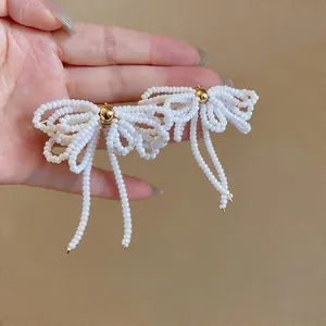 Gros plan d'élégantes boucles d'oreilles nœud en perles de verre blanches avec des glands