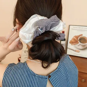 Close-up detail of a double-layered black striped and white satin hair scrunchie accessory