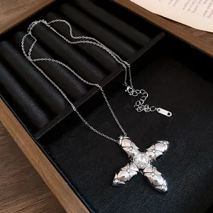 Close-up of a silver cross pendant with a central square crystal in a display tray.