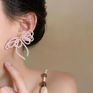 Gros plan détaillé d'élégantes boucles d'oreilles en nœud de perles roses portées par un mannequin