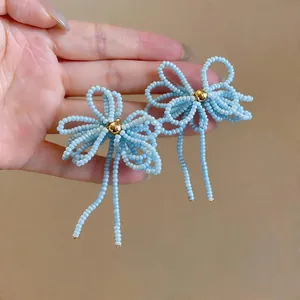 Détail des boucles d'oreilles nœud en perles de verre bleu clair avec perle dorée