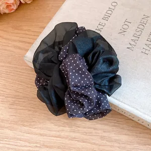 Detail view of the layered black sheer and polka dot fabric scrunchie on a vintage book