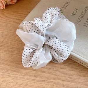 Detailed view of a white polka dot and sheer double-layered fabric hair scrunchie.