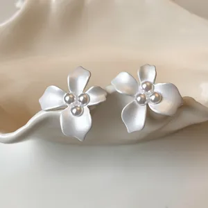 Detail view of matte white floral earrings with pearl center accents