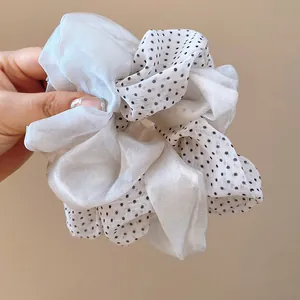 Close-up of double-layered fabric scrunchie with elegant black polka dot pattern