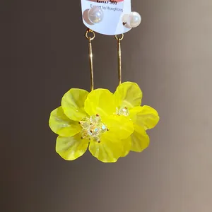 Close-up of yellow flower drop earrings with pearl studs and gold-tone finish
