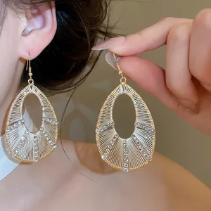 Vista dettagliata di orecchini a goccia traforati con eleganti accenti di strass.