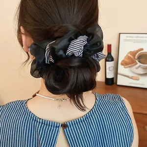 Close-up of a double-layer black and striped chiffon scrunchie styled in a bun.
