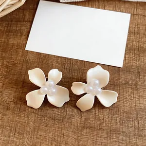 Detailed view of white flower stud earrings with elegant pearl centers
