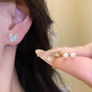 Detailed shot of delicate silver butterfly earring with rhinestones and pearl studs