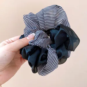 Macro detail view of a double-layered black and white striped organza fabric hair scrunchie
