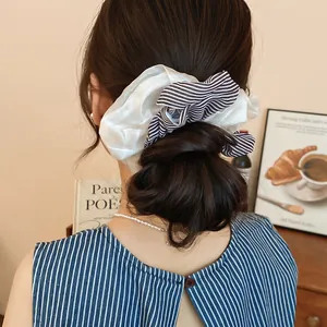 Detail view of a double-layered striped fabric scrunchie in a stylish low bun hairstyle