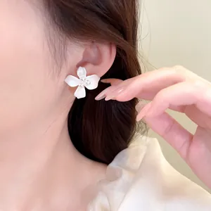 Close-up of elegant white flower pearl earring worn by model with unique petal design