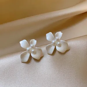 Detailed macro shot of elegant white enamel flower earrings with pearl cluster center