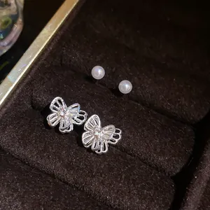 Detailed close-up of silver butterfly earrings with elegant white pearl studs.