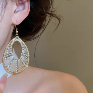Dettaglio di eleganti orecchini a goccia con strass indossati da una modella.