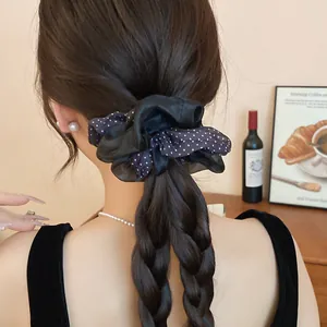 Elegant close-up view of a black silk scrunchie with polka dots on a braided hairstyle.