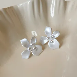 Detailed macro view of elegant matte white flower stud earrings with central pearls