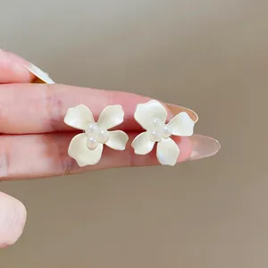 Macro view of cream white oil-drop flower stud earrings with three central pearls