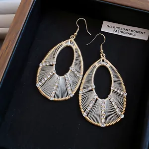 Primo piano di eleganti orecchini a goccia traforati con strass lucidi e dettagli intrecciati