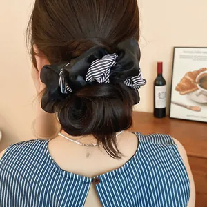 Detailed view of an elegant black and white striped fabric scrunchie styled on a hair bun