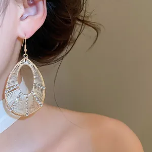 Eleganti orecchini a goccia d'oro con strass scintillanti indossati da modella asiatica
