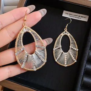 Dettaglio di orecchini a goccia intrecciati in stile boho con strass lucidi
