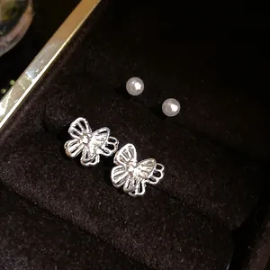 Detailed macro shot of silver filigree butterfly earrings and pearls in a jewelry box