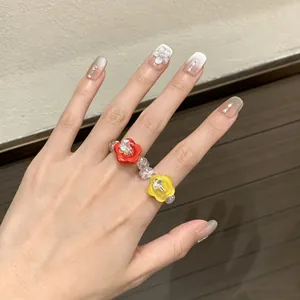 Hand-made beaded resin ring with colorful flower buttons worn on a woman's hand detail