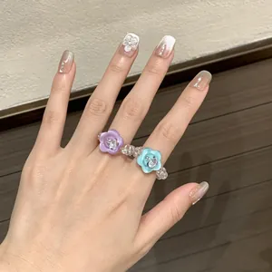 Detailed view of a handmade beaded resin ring featuring purple and blue flower buttons