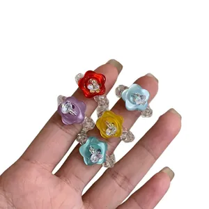 Set of handmade resin flower button beaded rings in five colors shown on a hand