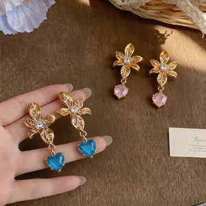Macro view of 18k gold plated flower stud earrings with elegant blue heart crystals