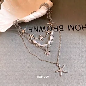 Multi-layer silver necklace with starfish and pearl pendants for beach vacations.
