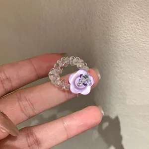 Detailed view of a handmade purple resin flower ring with clear beads and charm