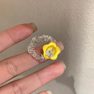 Close-up of handmade beaded ring with yellow flower button and sparkling crystal center