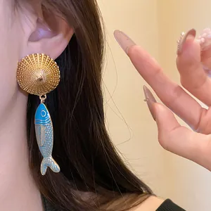 Detailed view of model wearing vintage enamel fish drop earrings with gold sun disk