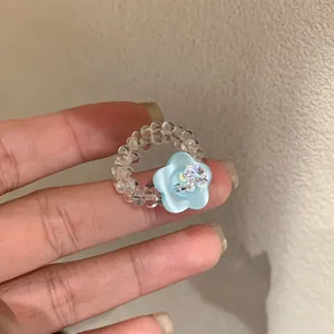 Close-up of handmade beaded ring with a delicate light blue resin flower and crystal.