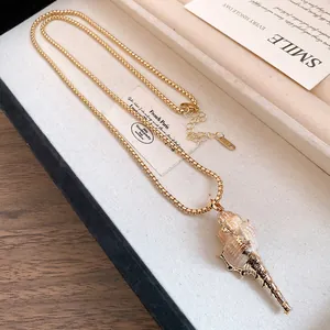 Détail d'un collier pendentif en coquillage naturel plaqué or dans une boîte cadeau