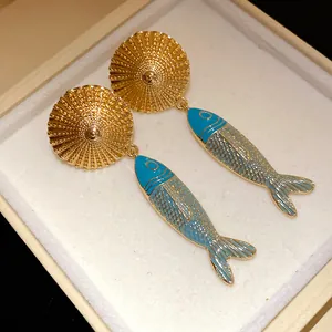 Detail of luxury vintage gold plated fish drop earrings with blue enamel in gift box