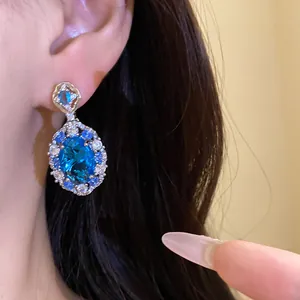 Primo piano di orecchini pendenti in argento con zircone blu ovale e dettagli in cristallo