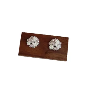 Elegant floral stud earrings featuring lavender and white pearls on a rustic wooden stand