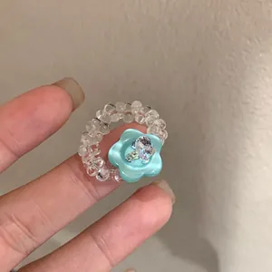 Detailed close-up of a handmade beaded ring with a light blue resin flower and crystals.